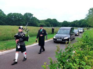 Hearse drivers following a service with a bagpiper