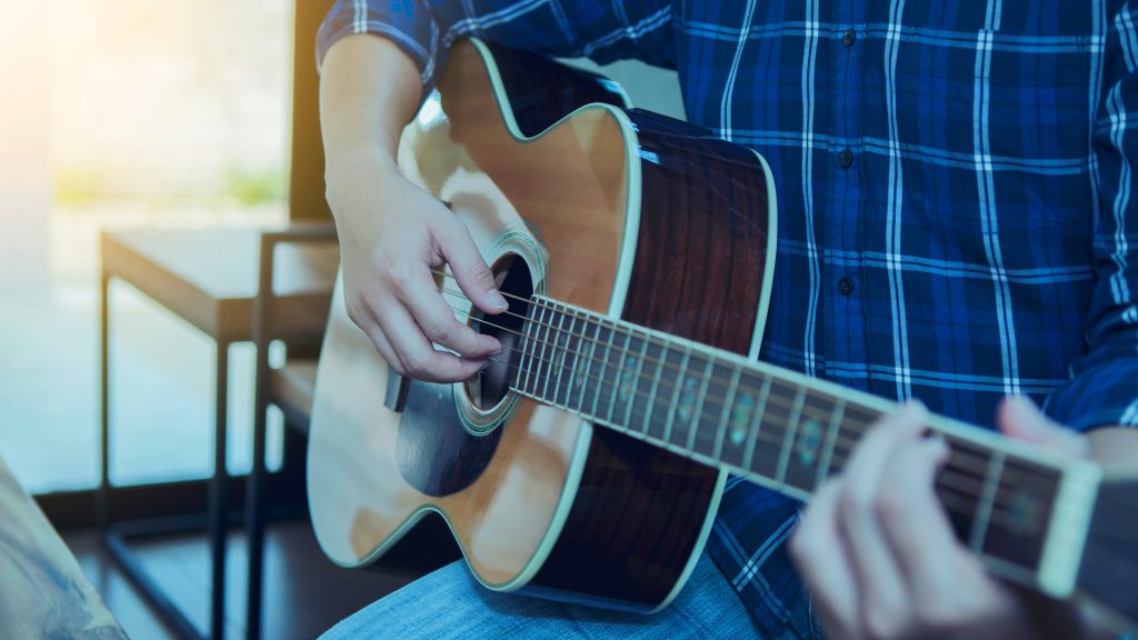 Close up shot of a man playing the acoustic guitar