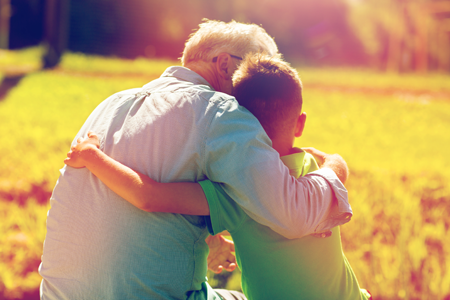 Young man and grandfather hugging outdoors
